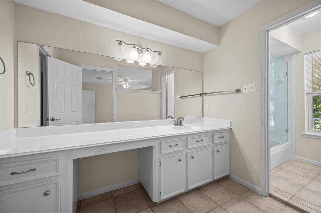 Primary bathroom with extended vanity, large wall mirror and access to a tiled shower and tub area.