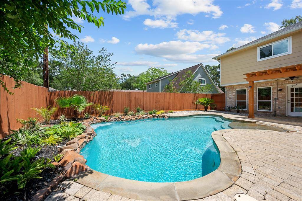 Beautiful backyard with a freeform pool, lush landscaping and a paved patio ideal for entertaining and summer barbeques.