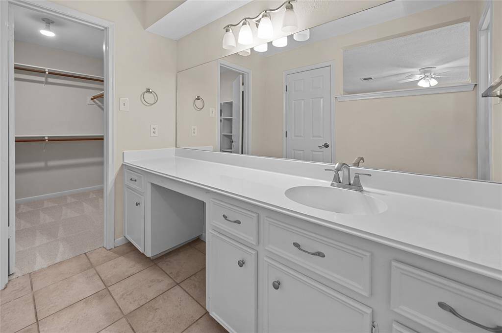 Primary bathroom with lots of countertop space, large mirror and access to a spacious walk-in closet.