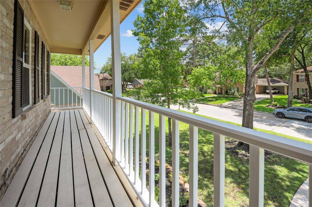 Charming second-story balcony with white railing and a peaceful view of the tree-lined street.