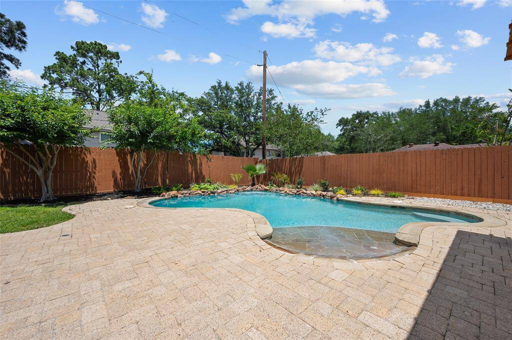 Private backyard oasis with a sparkling pool, rock landscaping, and spacious paver patio.