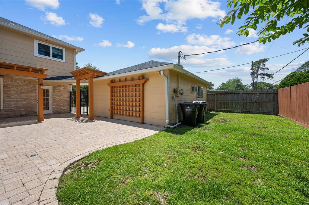 Side yard with grassy area, privacy fence, and direct access to the patio and detached garage.