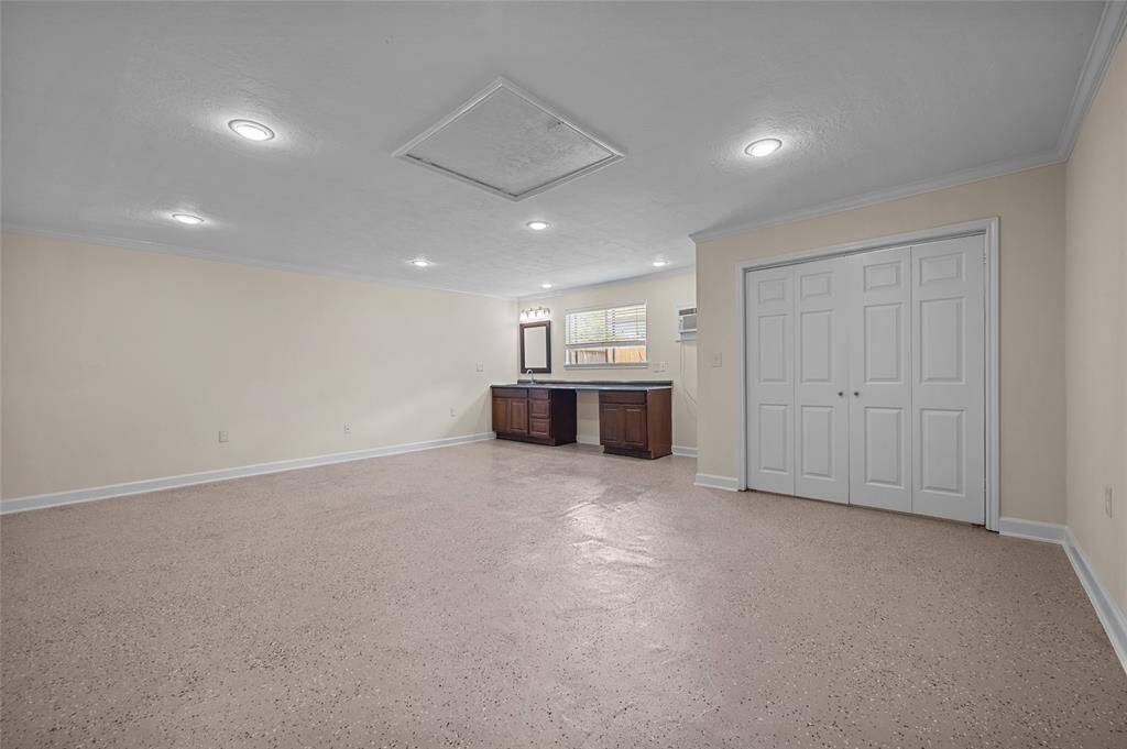 Spacious flex room or workshop in garage with built-in cabinetry, closet, and speckled epoxy flooring.