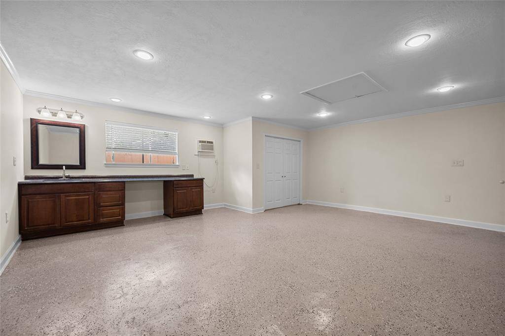 Spacious flex room or workshop space with built-in cabinetry, closet, and speckled epoxy flooring.