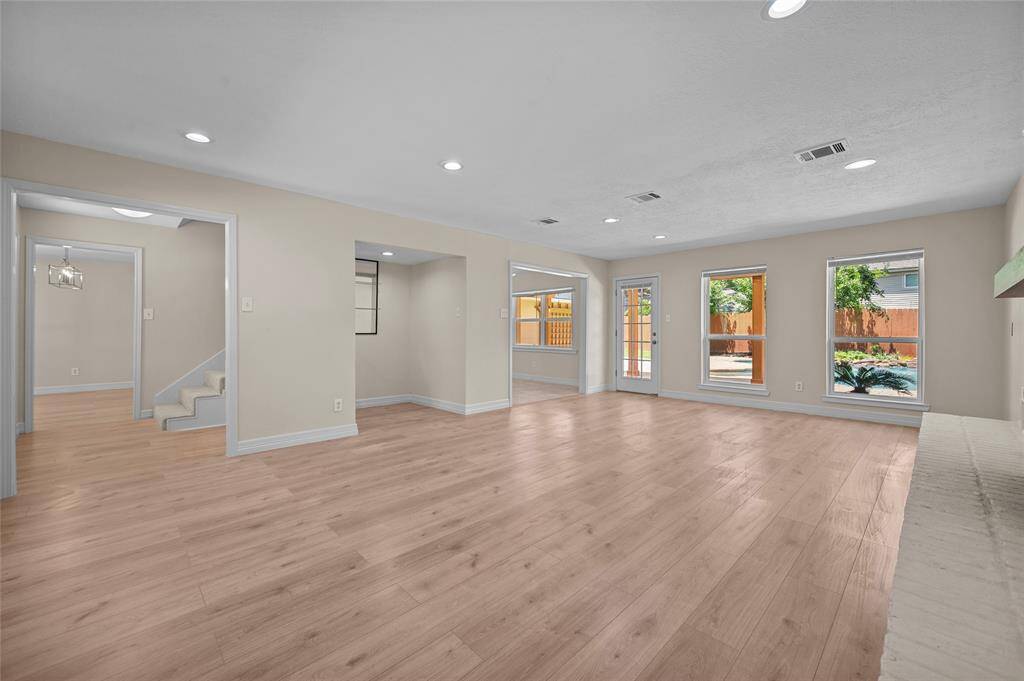 Open-concept living space with vinyl flooring, recessed lighting, and large windows overlooking the backyard pool.