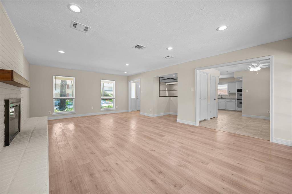 Spacious living area with fireplace, wood floors, and open access to the kitchen and dining spaces.