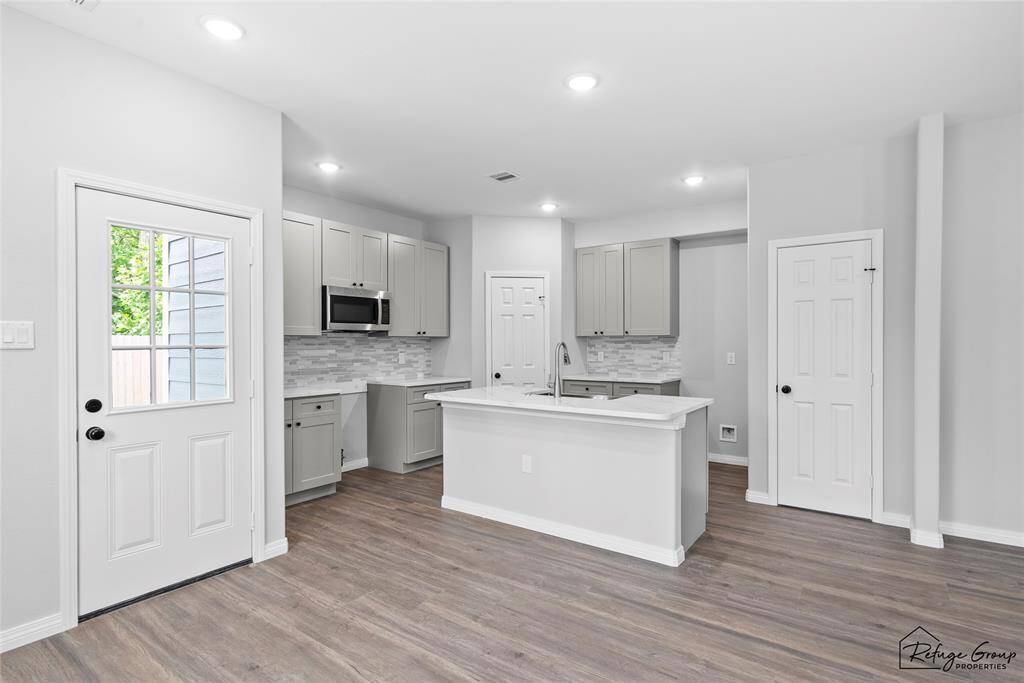 Kitchen features stainless steel microwave and gas stove (to be installed prior to closing) as well as an island with Quartz countertops