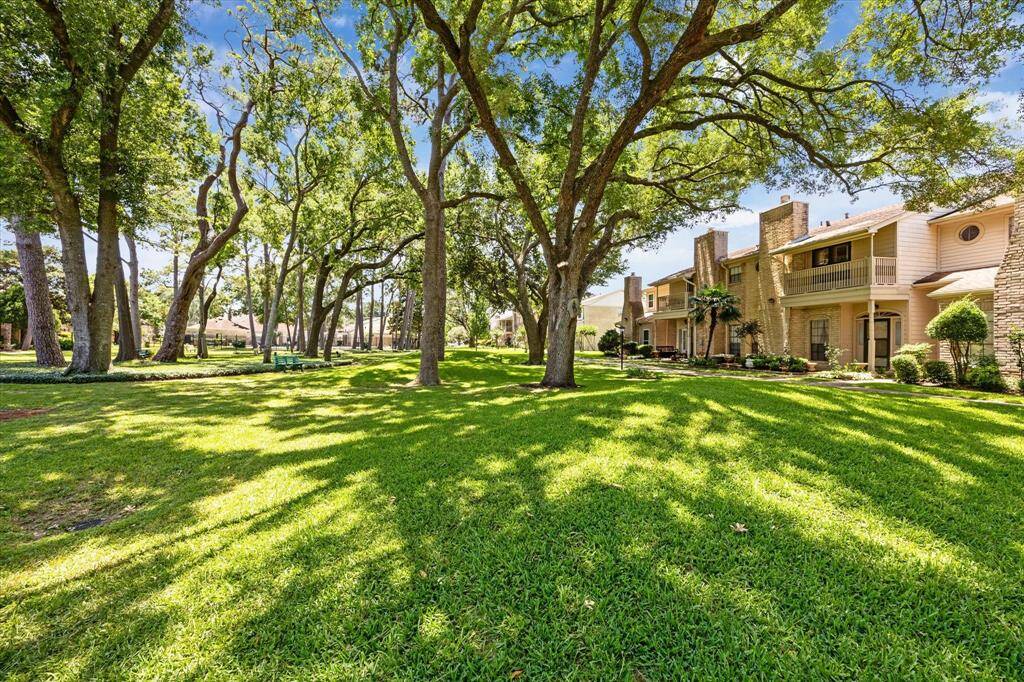 This photo showcases a charming residential area with well-maintained lawns and mature trees providing ample shade. The homes have a classic design with brick and wood exteriors, offering a peaceful and inviting neighborhood atmosphere.