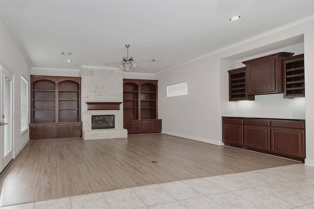 Family room with stone fireplace, wood floors, custom built-ins