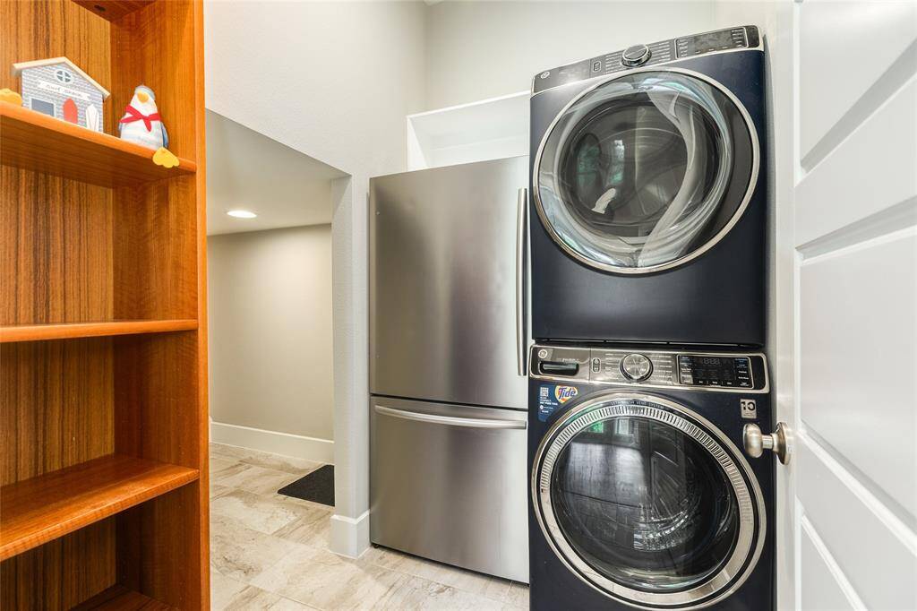 You're going to love this. The full-sized stacking washer and dryer and full-sized extra fridge stay with the house in huge laundry room. Notice the large, walk-in space under the steps... this is the perfect spot for Spot! The doggie door to the custom dog run on the East side of the house is here and this makes the perfect area to coral the fur babies when entertaining.