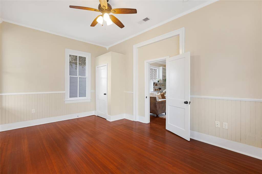 Unit 1: Bright and spacious bedroom. Located just off the living room, this first bedroom features soaring ceilings, glowing hardwood floors, and timeless trim details that capture the home’s historic charm.