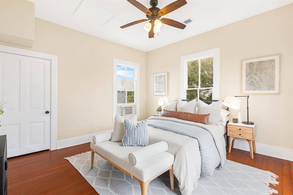 Unit 1: Suite perfection. This upstairs bedroom offers a peaceful retreat with rich hardwood floors, tall ceilings, and windows that frame the treetops outside.