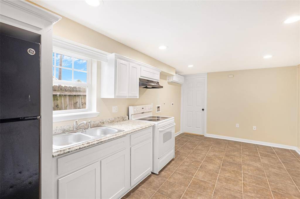 Unit 2: Natural light and functionality. Crisp white cabinets, granite-style formica countertops, and a picture-perfect window over the sink bring charm and light into this kitchen setup.