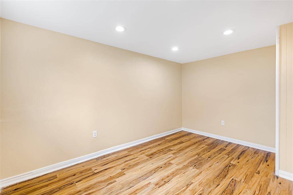 Unit 2: Downstairs retreat. Tucked away on the lower level, this private bedroom features warm wood-style flooring and recessed lighting—perfect for guests, a home office, or your own quiet escape.