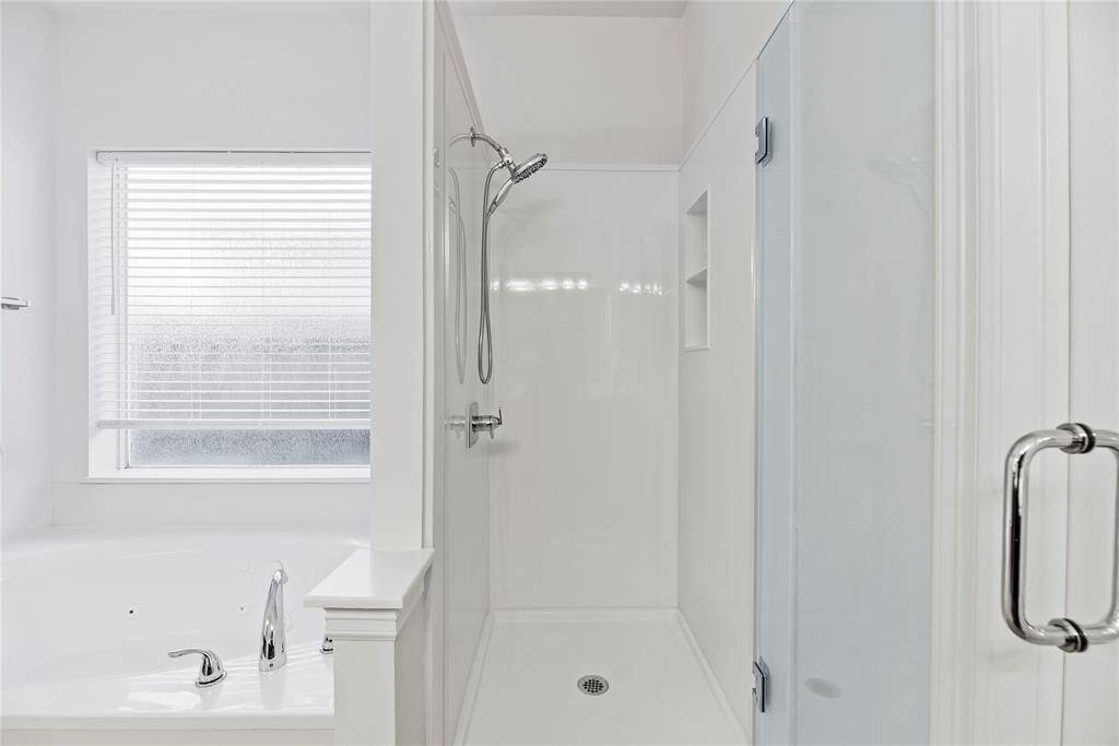 Matching tile work in the shower provides consistency in design. Early mornings are made brighter and warmer in the spacious shower featuring a built-in shelf for self-care items!