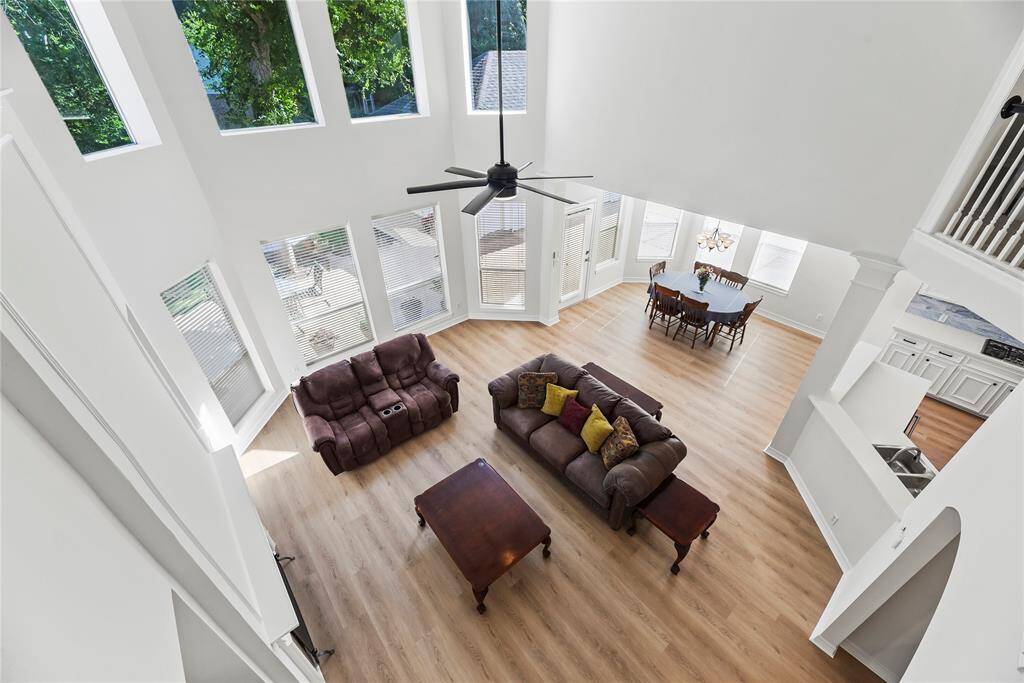 From the upstairs, enjoy a striking view overlooking the living room's open layout and soaring ceilings. The expansive windows and natural light create a bright, airy feel that highlights the room’s spacious design.