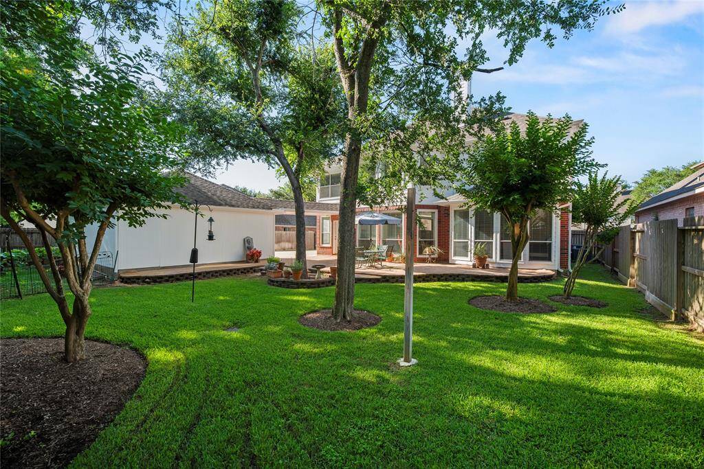 Completely level green, the backyard is shaped for playing and gardening.