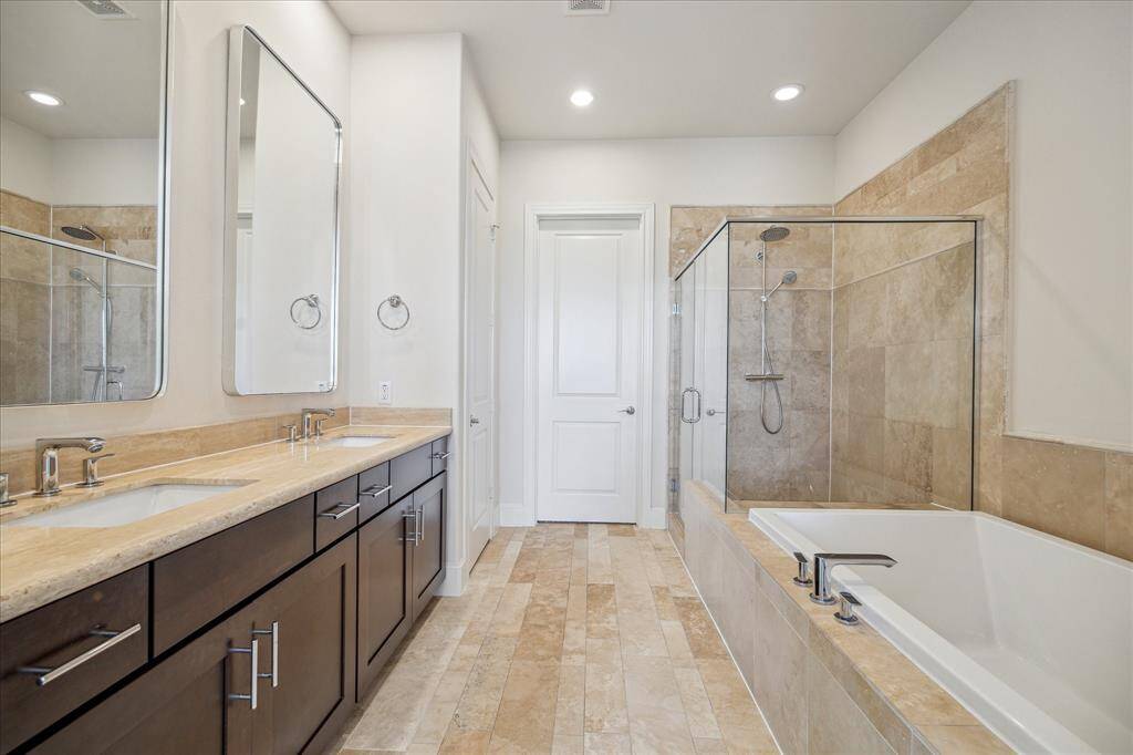 Double doors open to the Primary Bathroom featuring his/her vanities with ample cabinet space, seamless glass standing shower, tub, recessed lighting & a homeowner's dream....a large WALK IN closet.