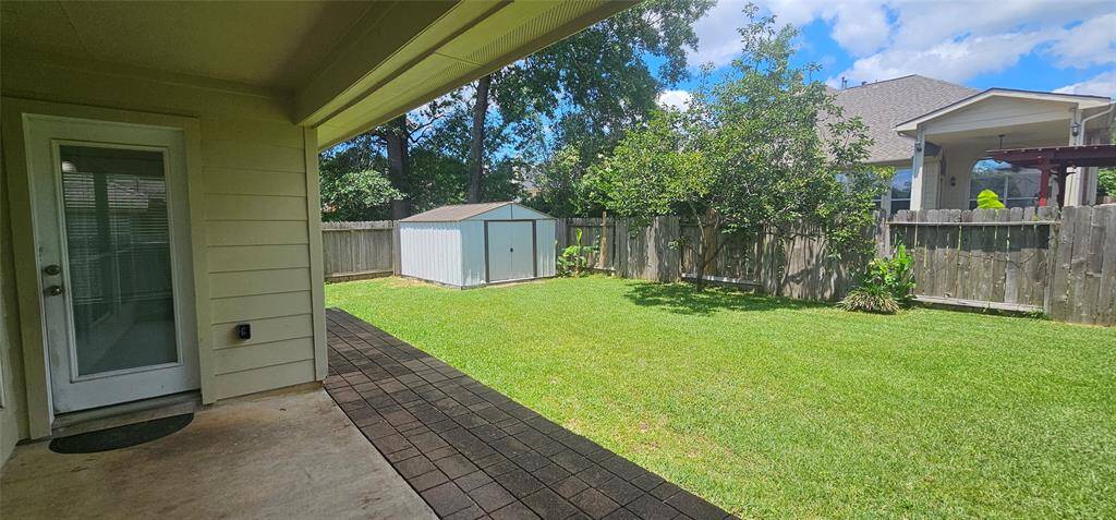 Covered patio with fully fenced backyard with a shed included