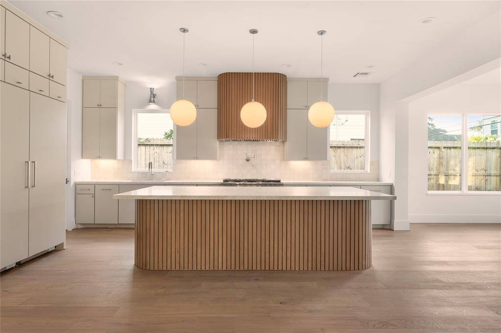 Natural light streams into the classic contemporary kitchen. A rounded fluted island adds a unique welcoming touch.