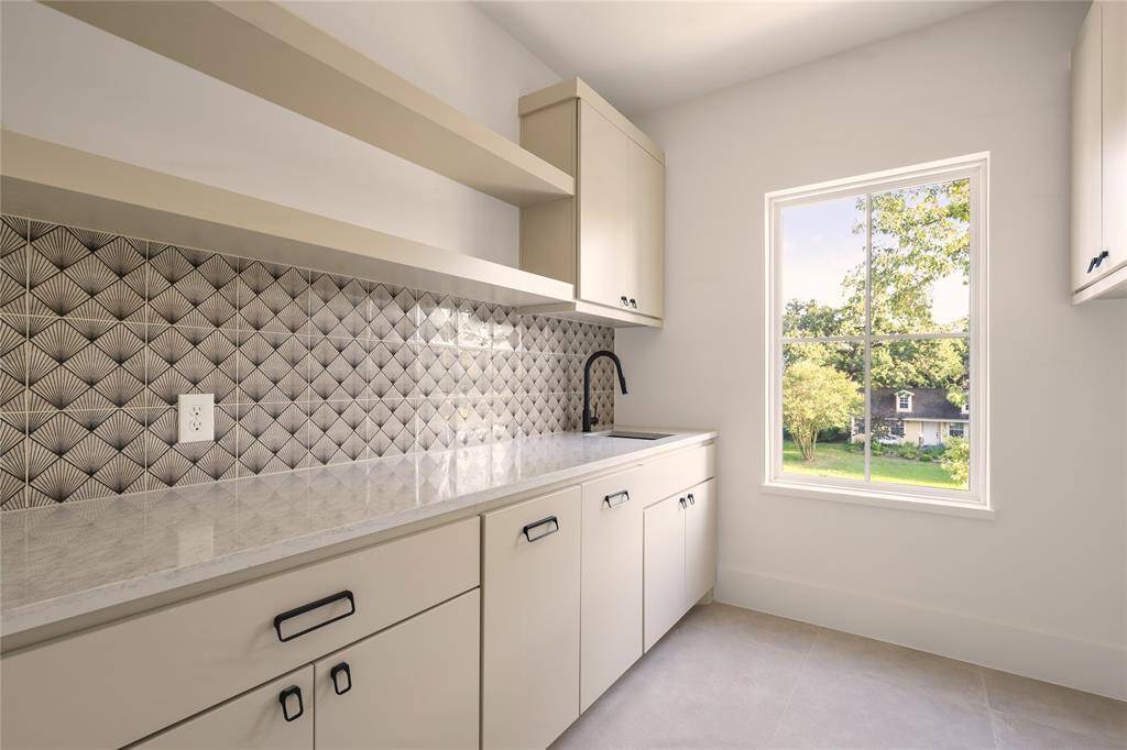 The Laundry room features Carrara Quartz countertops and a fun patterned backsplash as well as natural light.