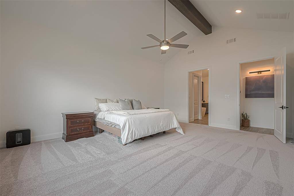 The primary bedroom boasts soaring ceilings with elegant decorative beams.