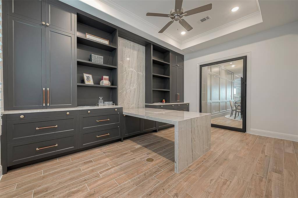 Step into your private study through the sleek cantilever door and admire the elegant built-in desk with a stunning waterfall edge and custom cabinetry
