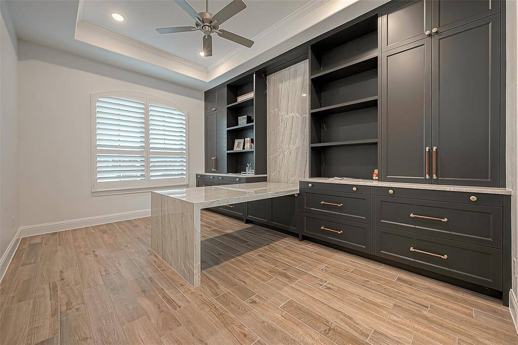 This modern home office with ample built-in storage, featuring sleek custom cabinetry and a custom waterfall desk.