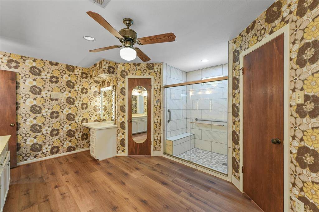 The Primary Bedroom boasts two closets, and the Primary En Suite Bathroom here, offers TWO MORE closets flanking the recently updated Glass Shower, with handrails and a built in bench seat. The built-in vanity offers custom vanity lighting.