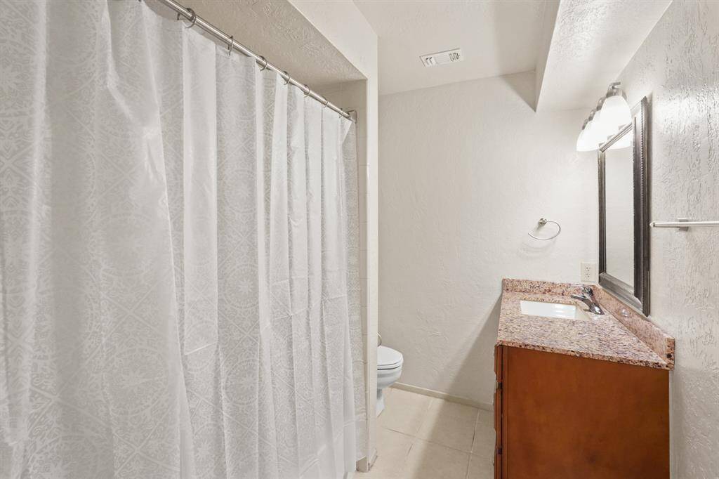 The full bathroom with wood stained cabinets, a spacious tub and shower, and large vanity with granite counters, is located just off the bedroom!
