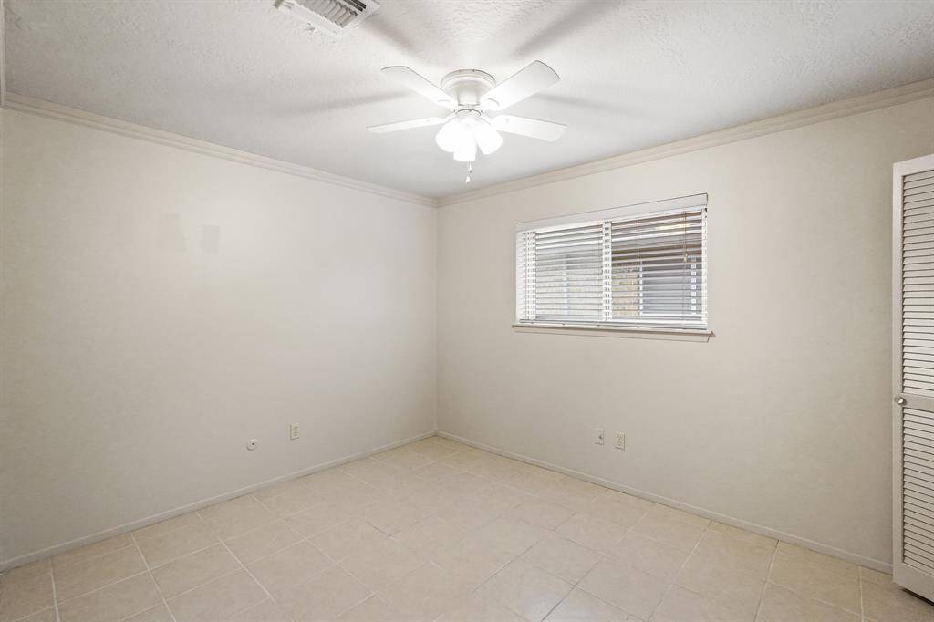 This spacious secondary bedroom features fresh paint, a spacious closet, a ceiling fan, and ceramic tile flooring.