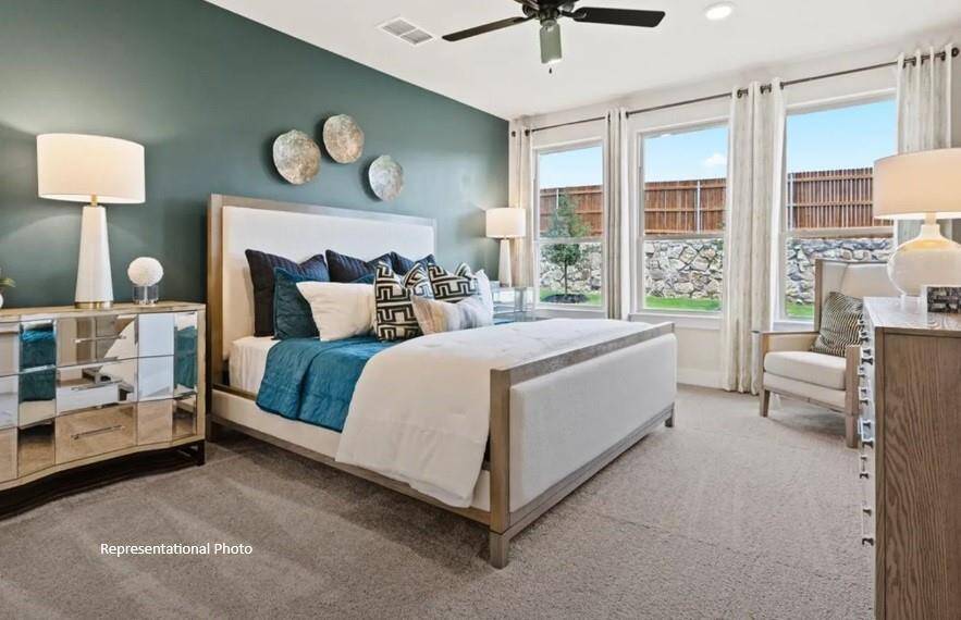 As you enter the primary bedroom, you’re greeted by an abundance of natural light pouring in through large, beautifully framed windows, casting a warm glow on the soft, neutral tones of the walls.