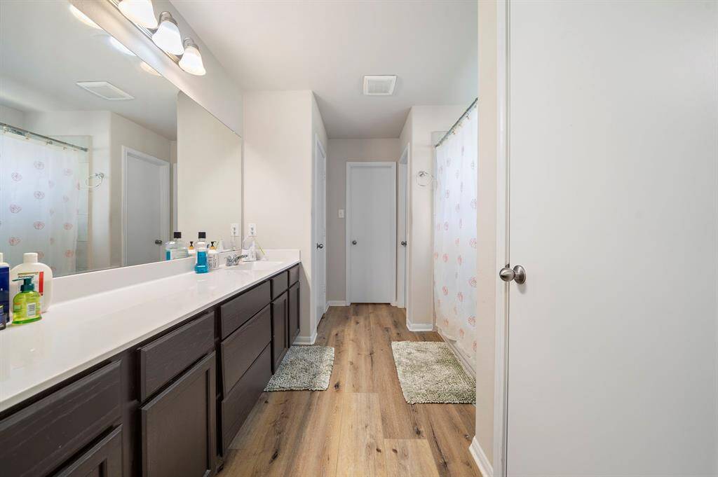 This bathroom features a spacious dual-sink vanity with ample storage, a large mirror.