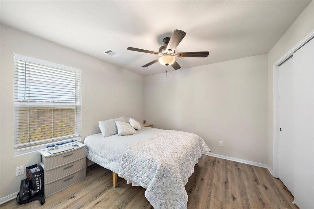 This bedroom features a cozy layout with a ceiling fan, and natural light from a window. It has high-end flooring and neutral walls, creating a calm and inviting atmosphere.