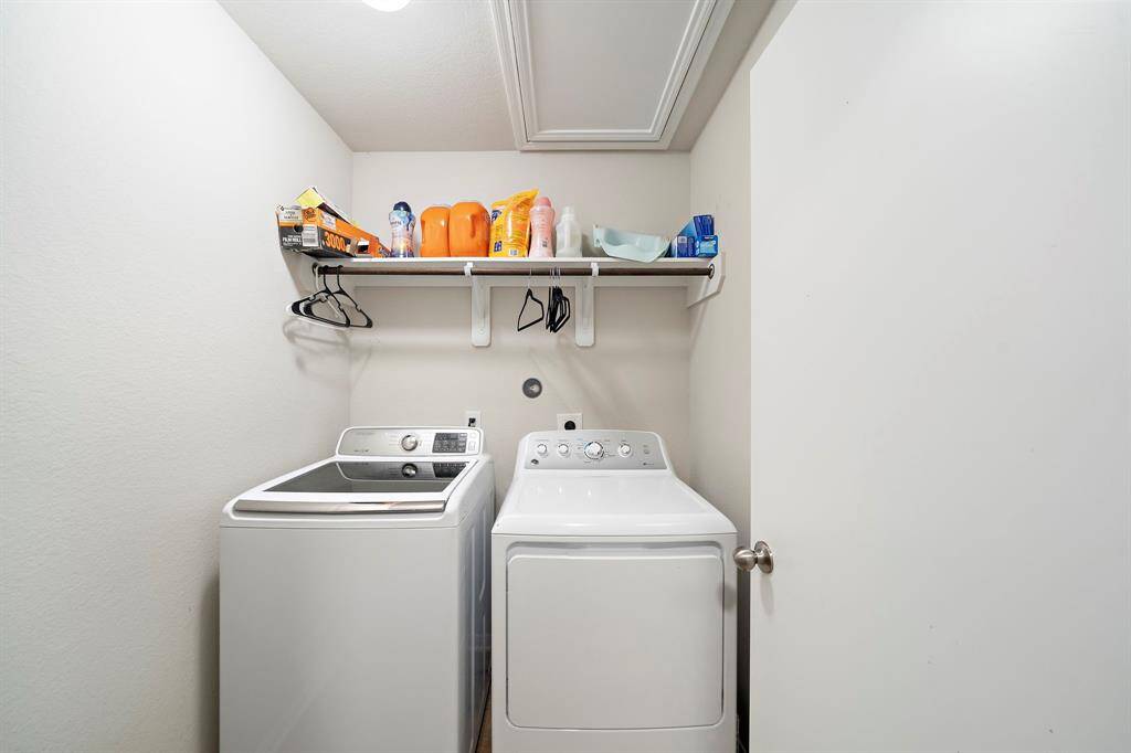 This photo shows a laundry room featuring a washer and dryer. Above them, a shelf provides storage space for detergents and other laundry essentials. The room is well-lit and efficiently organized.