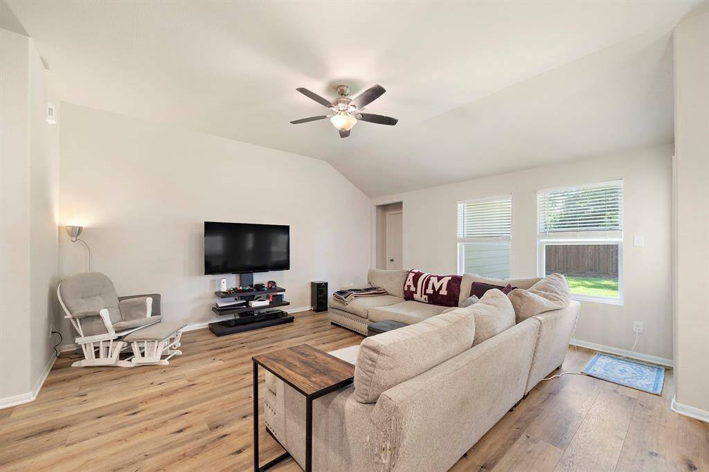This living room has high-end vinyl flooring, ample natural light from large windows, and a ceiling fan for comfort.