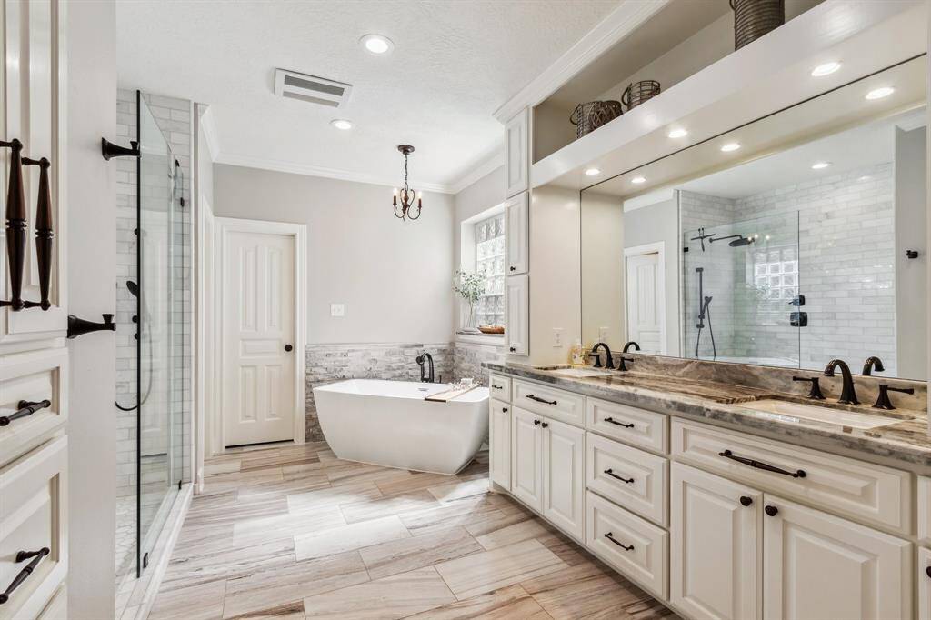 Spa like primary bath features custom cabinetry, linen closet with drawers, large shower and relaxing soaking tub.