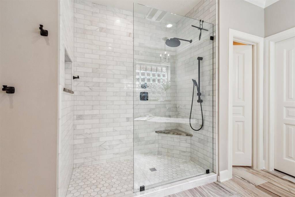 Large walk in shower with corner bench and shampoo niche.