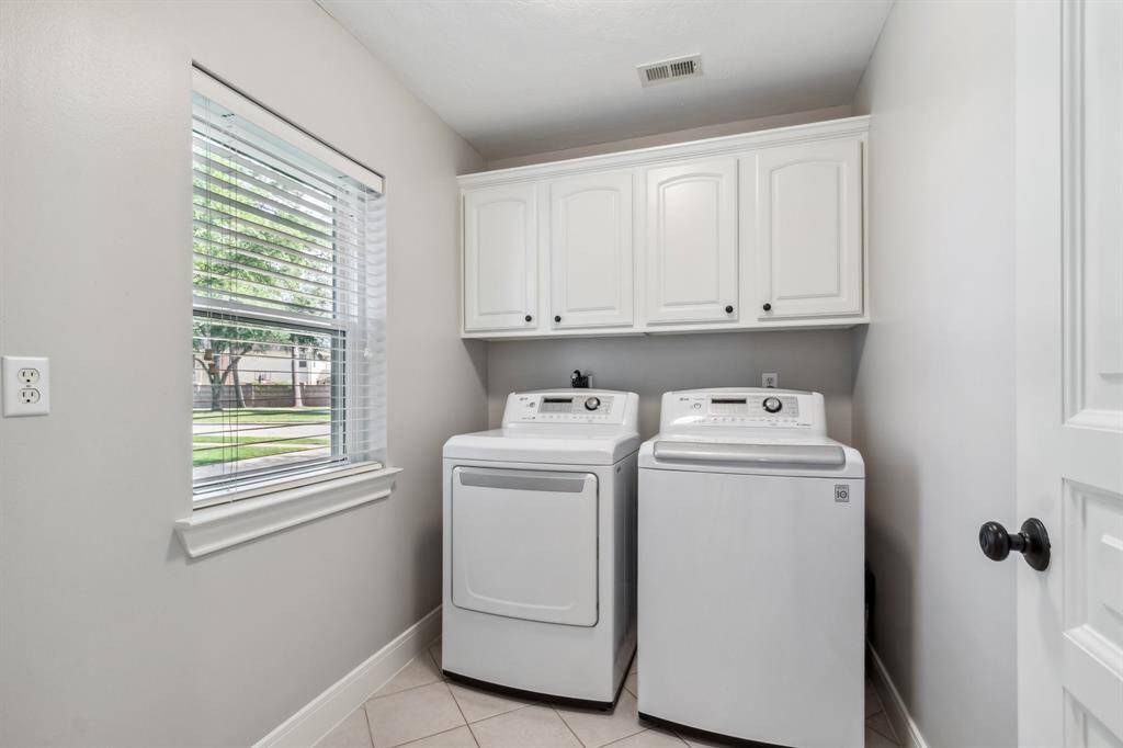 Laundry room with cabinets above.