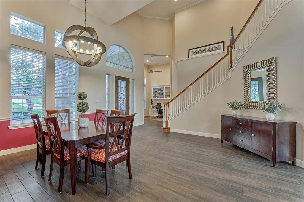 The formal dining room is bright and airy, featuring a soaring two-story ceiling and wood-look tile flooring that flows seamlessly throughout for a cohesive look.