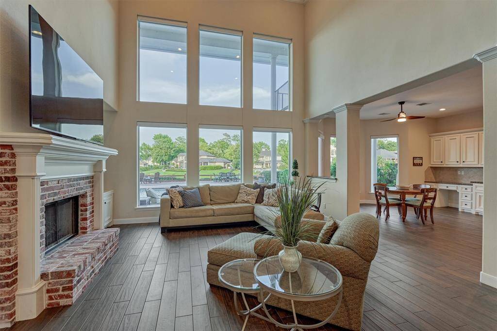 The two-story living room showcases floor-to-ceiling windows with automatic shades, flooding the space with natural light.