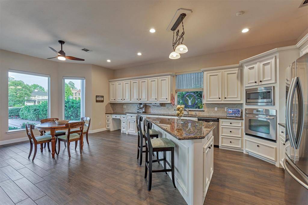 The expansive kitchen features abundant counter and cabinet space with multiple storage options, while the flooring beautifully complements the cream cabinetry and granite countertops for a warm, cohesive look.