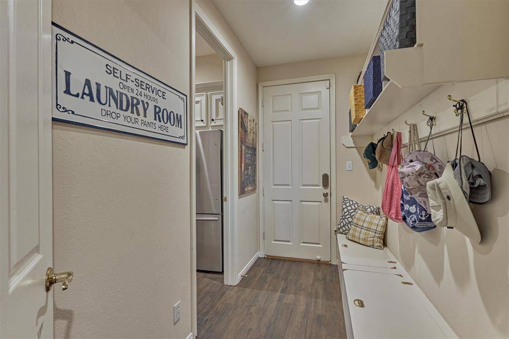 The mudroom just off the garage is ideal for dropping bags and shoes, featuring a convenient bench with built-in storage. The laundry room is located just to the left.