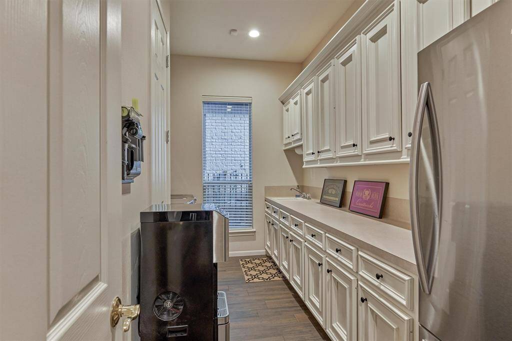 The laundry room has an expansive folding counter, closet, sink and space for an extra refrigerator or freezer. A window provides natural lighting to brighten the space.