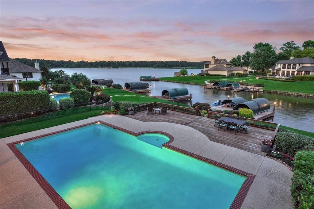 The balcony view showcases the lush layers of landscaping, pool, and serene ambiance of this location on the lake.