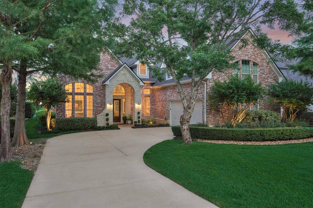 A closer look at the front of the home reveals mature, lush landscaping accented by elegant landscape lighting.