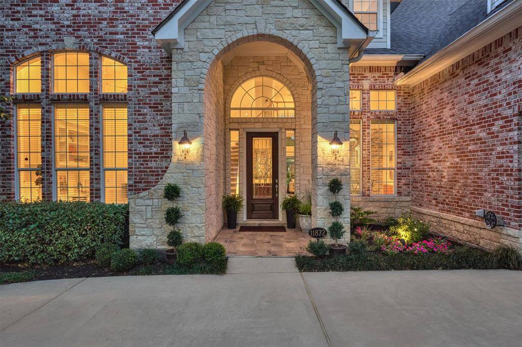 The covered entry is beautifully accented by arched stone detailing and meticulous landscaping