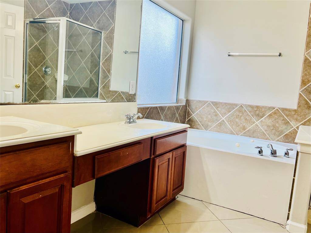 Primary bathroom is complete with a dual sink vanity, freshly painted walls, jetted tub, shower and huge walk-in closet.
