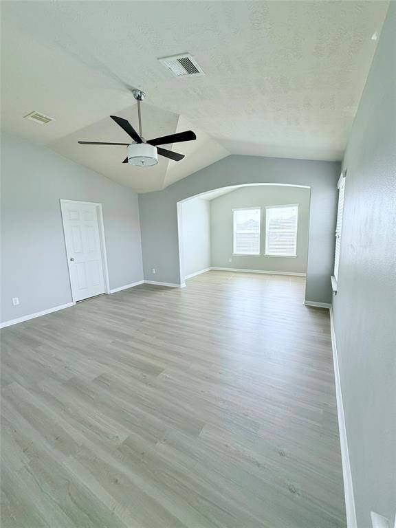 Spacious primary room featuring elegant flooring, modern ceiling fan, and abundant natural light from large windows, offering a serene retreat.