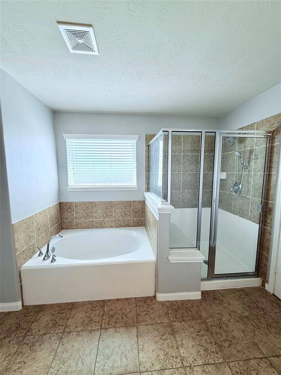 Luxurious primary bath featuring a spacious soaking tub, separate glass-enclosed shower, and elegant tile accents.